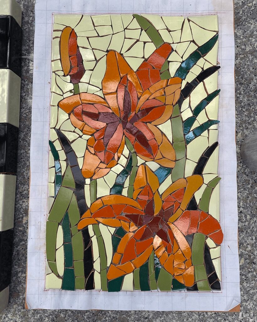 mosaic tile pieces depicting daylilies and leaves, arranged in order on a paper diagram