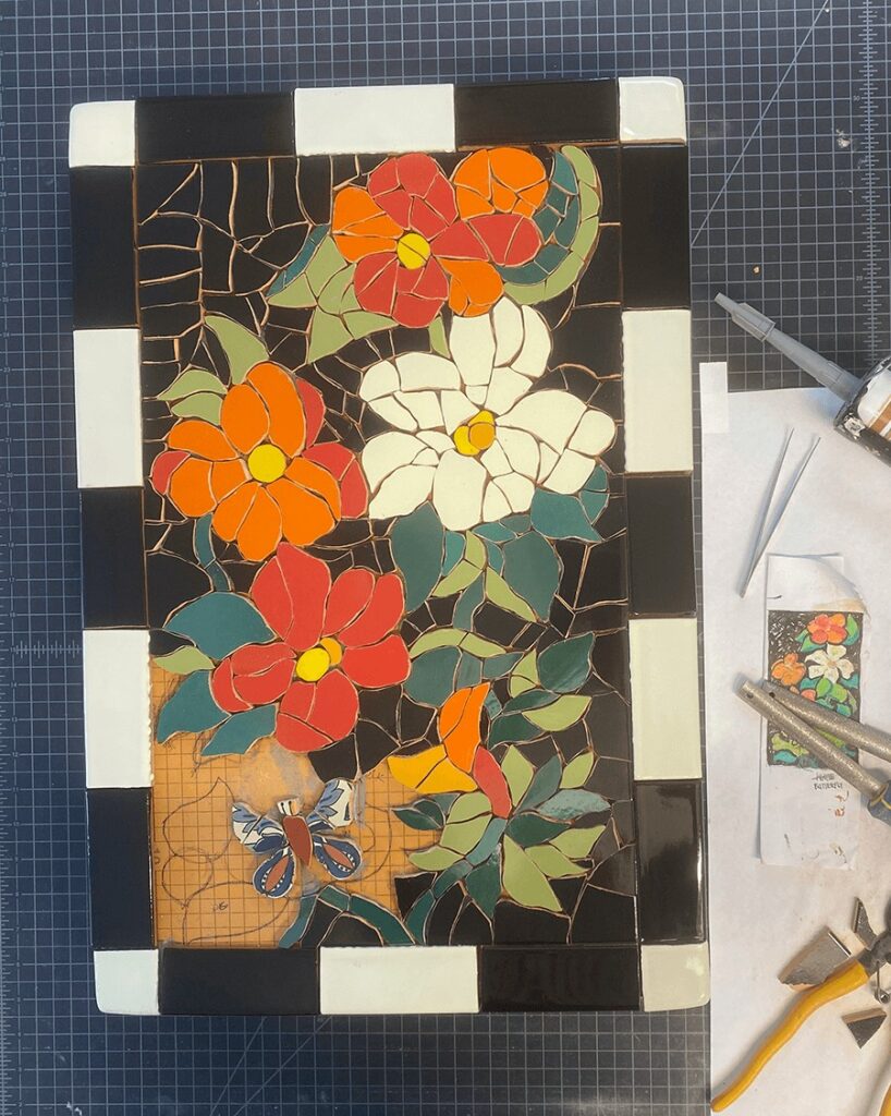 infilling the background of the motif with black pieces of broken tile